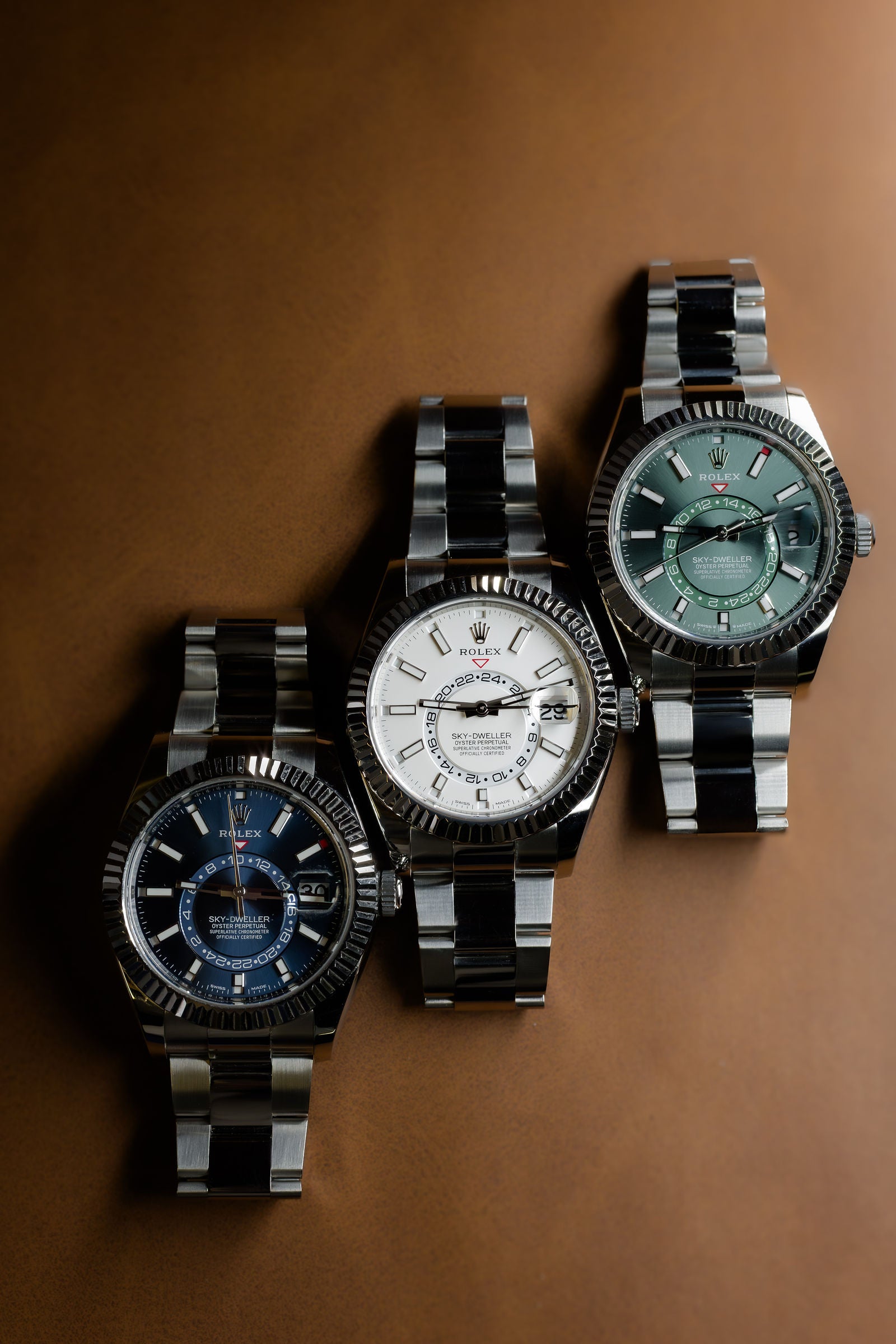Three Rolex Sky-Dweller watches photographed on warm brown leather